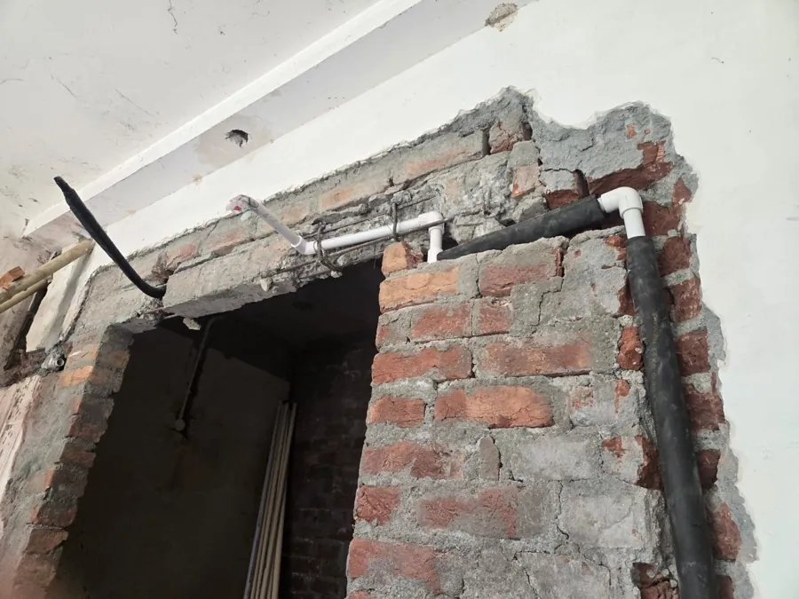 Construction site: masonry above a doorway cut open after building to run services that were never set out.